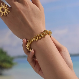 Bohemian gold sun ring and spiked heart charm bracelet set worn by a model at the beach