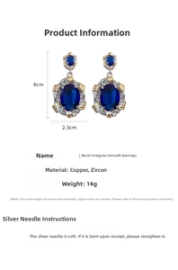 Detailed view of large blue resin oval earrings with gold and silver trim edges