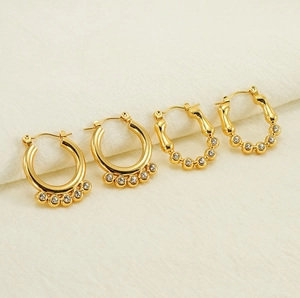 Détail de boucles d'oreilles créoles en titane doré avec perles et incrustations diamant