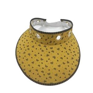 Detail view of yellow sun visor featuring black butterfly prints and metal eyelets