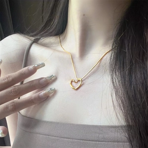 Minimalist twisted heart pendant necklace in gold stainless steel worn by a model
