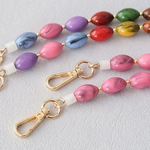 Détail de la chaîne de perles en résine marbrée colorée avec fermoirs mousquetons dorés