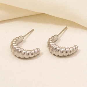 Macro detail of silver twisted rope earrings with matte finish on textured background