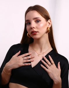 Detailed view of 18K gold plated jewelry set including earrings, necklace and rings on model