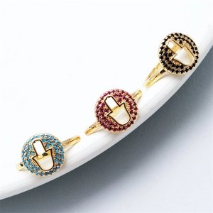 Detailansicht von drei goldenen Hamsa-Ringen mit bunten Zirkonias auf weißer Keramik