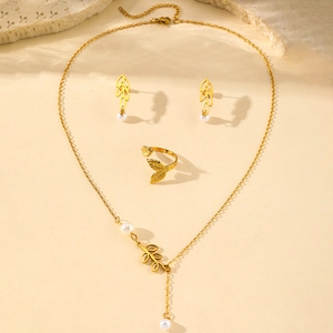 Golden leaf jewelry set with pearls including necklace earrings and ring on stone decor