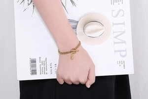 Detail eines goldfarbenen zweilagigen Kettenarmbands mit OT-Verschluss und Ananas-Anhänger