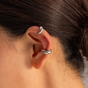 Close-up of silver stainless steel C-shaped ear cuffs worn on a model's ear