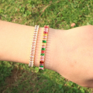 Macro detail of gold tennis bracelets featuring colorful and white cubic zirconia stones