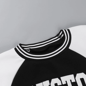 Close-up of the striped rib knit collar and raglan sleeve detail on a black-white sweatshirt