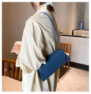 Blue crocodile pattern baguette shoulder bag styled in a cozy cafe setting