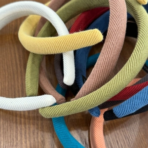 Détail de serre-têtes en maille colorée empilés sur un support en bois naturel