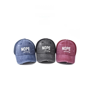 Three washed cotton baseball caps in blue, grey, and burgundy with NOPE slogan