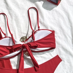 Detail of red bikini set featuring a gold metal hardware buckle and front bow tie design