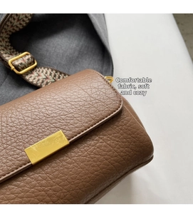 Détail d'un sac bandoulière en cuir marron avec sangle jacquard et boucle dorée