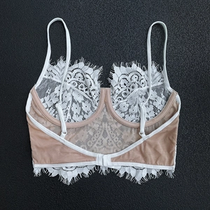 Lingerie fine en dentelle blanche avec dos nu et détails en maille sur fond gris texturé