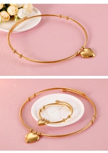 Detailed view of gold heart jewelry set including wire choker and matching bracelet
