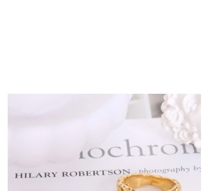 Close-up of golden ring with handmade hammered texture on a minimalist white background