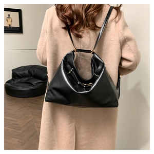 Detail of a large black leather tote bag worn with a khaki wool coat for a chic look