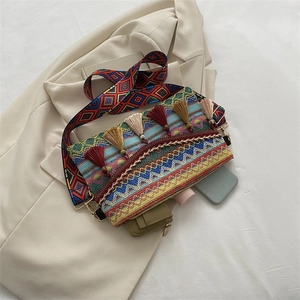 Detail of colorful woven ethnic shoulder bag with vibrant tassels and wide strap