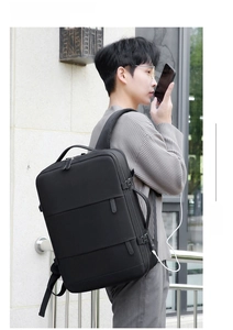 Detail shot of black minimalist travel backpack worn by model, showing durable fabric and straps.