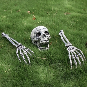Realistic Halloween skeleton skull and hand stakes emerging from the grass on lawn