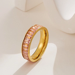 Detail of gold eternity ring with pink rectangular zircons on a white display