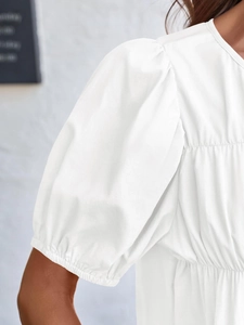Detailed view of the puff sleeve and pleated fabric texture on a white summer top