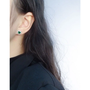 Elegant S925 sterling silver heart stud earrings with green zircon on ear model