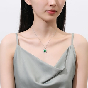 Elegant silver necklace featuring oval green emerald cut stone surrounded by white diamonds