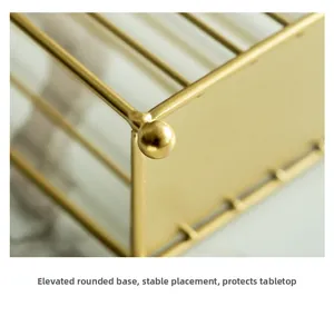Detail van de verhoogde ronde voet van een gouden metalen servettenhouder op marmer