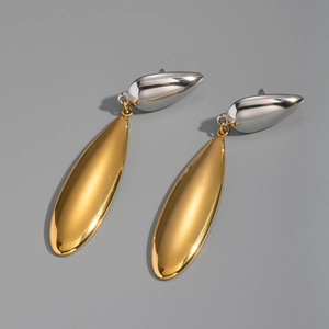 Détail de boucles d'oreilles bicolores minimalistes en forme de goutte argent et or