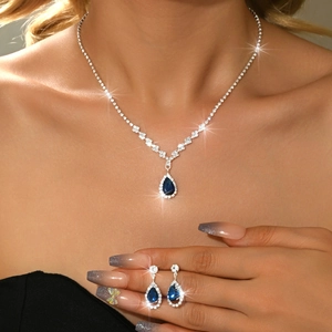 Close-up of sparkling pear-shaped blue gemstone jewelry set including necklace and earrings