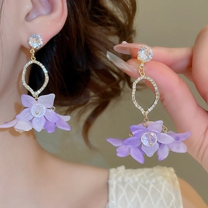 Detail of purple flower drop earrings with crystal accents and gold-tone finish