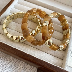 Close-up of three layered gold and amber resin beaded bracelets in a velvet jewelry box