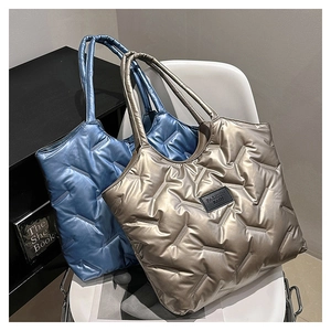 Gesteppte Tragetaschen in Silber und Blau mit Metallic-Effekt auf einem Stuhl