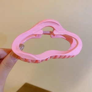 Gros plan d'une pince à cheveux rose ondulée montrant la structure creuse et le ressort