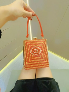 Detail of red evening clutch with beaded texture and sunflower crystal buckle