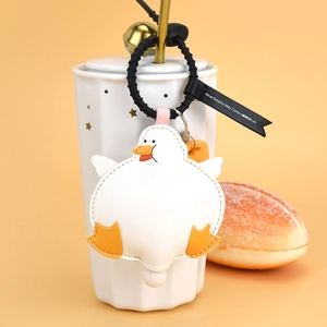 Creative white duck leather keychain pendant on a white cup with orange background