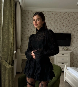Detail of black lace long-sleeve dress with high neck and sheer lantern sleeves design