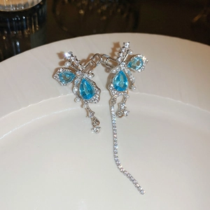 Détail du clip d'oreille papillon argenté avec gemme bleue, perles et longs glands