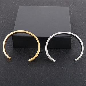 Detailed close-up of gold and silver minimalist concave steel cuff bracelets in a gift box