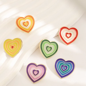 Set of six rainbow enamel heart pins in gradient colors on white wavy background