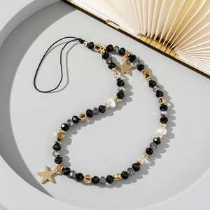Detail of beaded phone strap with black faceted beads and gold star pendants on a tray