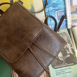 Dettaglio dello zaino in pelle marrone vintage su libri che mostra la trama retro