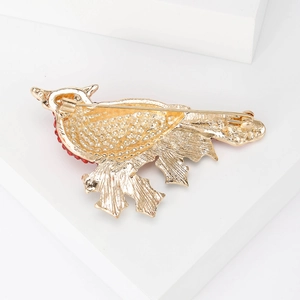 Back view of golden bird brooch showing secure safety pin and red crystal detail
