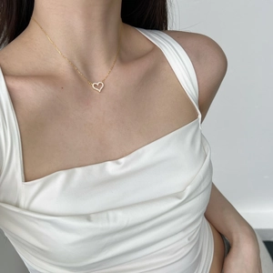 Close-up of a gold heart pendant necklace with zircon stones worn by a model