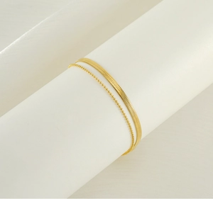 Detail view of 18K gold plated double layer anklet with snake and bead chains on white roll