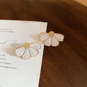 Détail de boucles d'oreilles fleurs blanches à billes dorées sur carte poétique