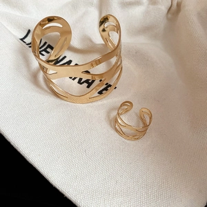 Close-up of gold hollow geometric cuff bracelet and ring set on fabric pouch